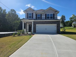 A charming two-story home with brick accents and sleek shutters in Scarlett Place by Adams Homes (Bowdon, GA).