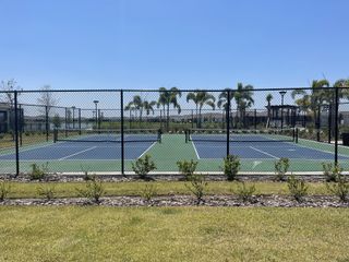 Well-maintained tennis courts surrounded by lush greenery, perfect for recreational play at Tohoqua Reserve by Pulte Homes (Kissimmee, FL).