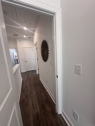 A bright hallway with rich hardwood flooring and modern decor, featuring white doors and recessed lighting.