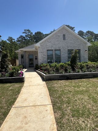 Street view A charming brick home with a lush garden and walkway in Westridge Cove by Coventry Homes (Conroe, TX).