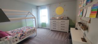 A vibrant kids' room featuring a colorful polka dot bed, artistic wall decor, and a spacious dresser.