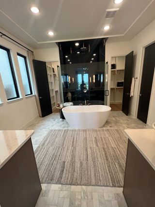 A luxurious bathroom with a sleek freestanding tub, spacious marble flooring, and ample natural light.