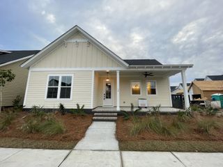 Street view Charming beige home with a welcoming porch and landscaped yard in The Domus Collection at Midtown Nexton by New Leaf Builders (Summerville, SC).