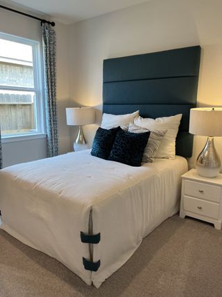 A cozy bedroom with a plush teal headboard, elegant bedside lamps, and patterned curtains for a touch of charm.