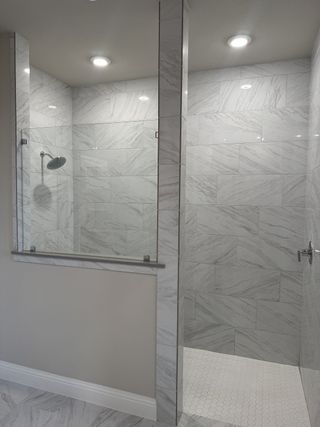 A sleek, modern shower with floor-to-ceiling marble tiles and elegant lighting.