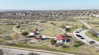A scenic community park with playgrounds and walking paths in Buffalo Crossing by Coventry Homes (Cibolo, TX).