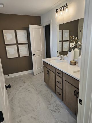 A chic bathroom with a marble-tiled floor, sleek wood vanity, modern lighting, and elegant wall art.