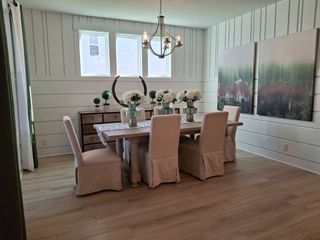 A sophisticated dining room with elegant seating, decorative molding, and chic artwork, illuminated by a stylish chandelier.