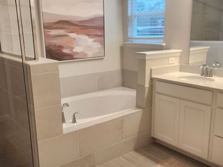 A serene spa-like bathroom with a built-in soaking tub, a glass-enclosed shower, and sleek neutral tile for a modern, relaxing retreat.