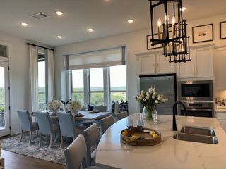 A modern kitchen and dining area with chic lighting, large windows, and elegant decor, offering a spacious, inviting ambiance.