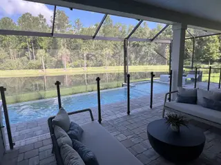 Model Home A serene screened patio with plush seating, overlooking a pool and natural pond views. Perfect for relaxation.