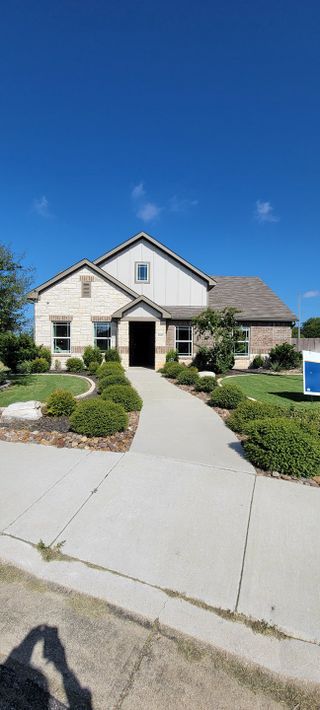 A charming brick home with lush landscaping in Cloud Country by Brightland Homes (New Braunfels, TX).