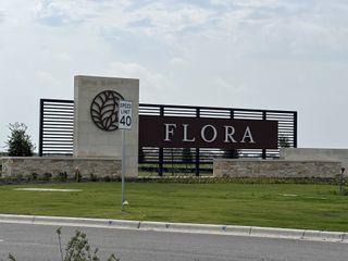 Entrance to Flora - 60' by Westin Homes in Hutto, TX, featuring a sleek sign and manicured landscaping.