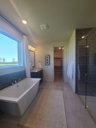 A spacious bathroom featuring a freestanding tub, glass shower, and elegant vanity with ample natural light.