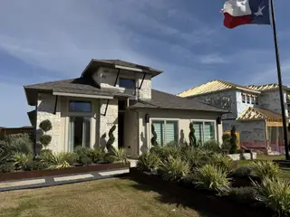 Street view A modern stone home with sleek lines and lush landscaping in Patterson Ranch 47' by Perry Homes (Georgetown, TX).