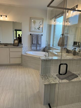 A luxurious bathroom featuring a glass shower, granite countertops, and a serene soaking tub with elegant fixtures.