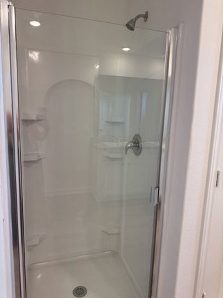 A sleek glass-enclosed shower with chrome fixtures and built-in shelves, offering a modern touch to the bathroom space.