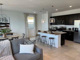 Model Home A modern open-plan kitchen and living area with sleek dark cabinetry, cozy seating, and contemporary lighting.