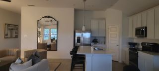 Model Home Modern kitchen with sleek stainless steel appliances, pendant lights, and a cozy adjacent living area.