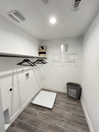 A modern laundry room with wood-style tile flooring, hanging rod, and stylish basket. Perfect for functional and sleek chores.