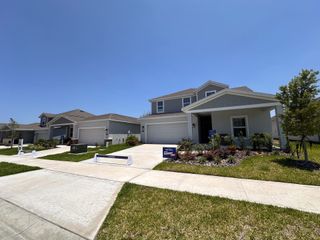 A row of newly constructed homes with well-manicured lawns, driveways, and signs indicating they are part of a sales event by Lennar. 