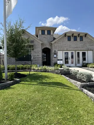 Street view A charming brick home with lush landscaping in Dellrose by Ashton Woods (Hockley, TX).