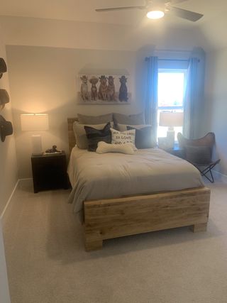 Model Home A cozy bedroom with a wooden bed, soft lighting, a plush carpet, and charming decor featuring dogs in cowboy hats.