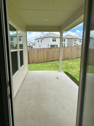 Model Home A cozy covered patio with a concrete floor, ideal for outdoor relaxation, overlooking a fenced backyard.