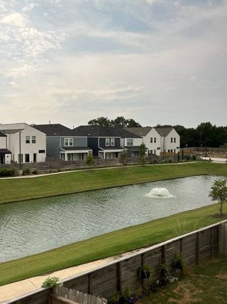 A picturesque community pond with elegant homes lining the shore in Cay Landing by First America Homes (Houston, TX).