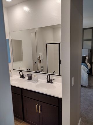 Model Home A modern bathroom featuring dual sinks, elegant black fixtures, and a large mirror for a sleek, contemporary feel.