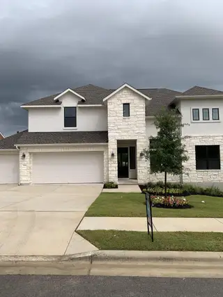 Street view A charming stone and stucco home with a lush lawn in Provence by Westin Homes (Austin, TX).
