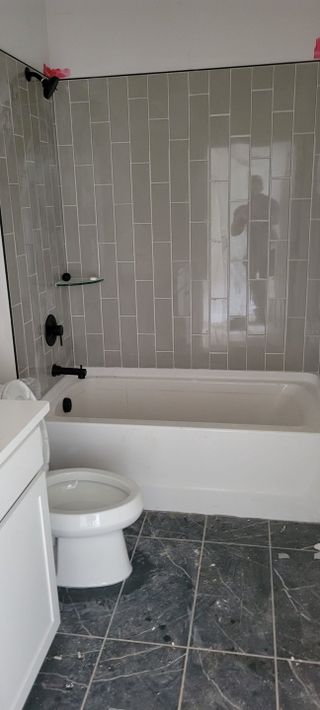 A modern bathroom featuring subway tile, a sleek bathtub, and a dark-tiled floor with elegant fixtures.
