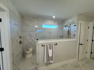 Luxurious bathroom with marble tiles, brass fixtures, and modern lighting, offering a spa-like atmosphere.