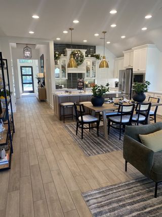 A chef’s dream kitchen with white cabinetry, gold pendant lighting, and festive decor, flowing seamlessly into the dining space.