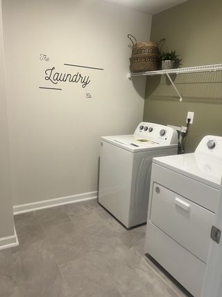 Modern laundry room with a washer, dryer, decorative basket, and tiled flooring.