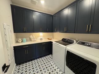 A chic laundry room with navy cabinets, geometric tile flooring, and modern appliances.