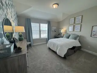 A stylish bedroom with a playful patterned accent wall, a full-size bed with soft blue pillows, plush carpeting, and coordinating blue curtains.