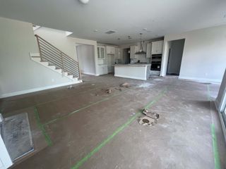 An open-concept interior under construction with a modern kitchen and sleek staircase.