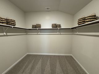 A spacious walk-in closet with carpet flooring, built-in shelves, and chic woven baskets for organized storage.