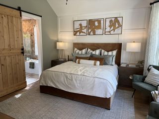 Model Home A cozy bedroom with a modern rustic design, featuring a wood sliding door, stylish artwork, and elegant lighting.