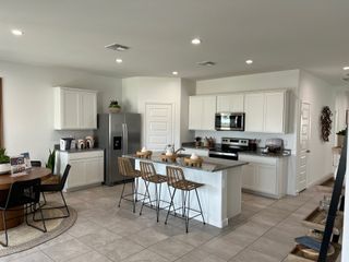 A modern kitchen featuring sleek white cabinets, a granite island, stainless steel appliances, and a cozy breakfast nook.