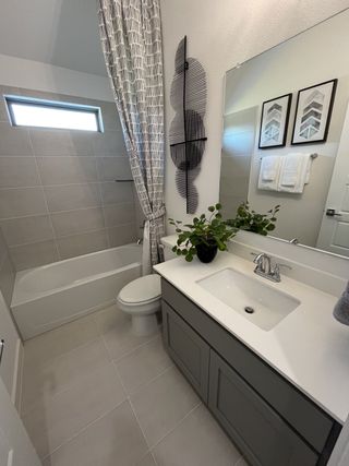 A chic bathroom featuring a tiled bathtub, sleek gray vanity, and decorative wall art for a modern touch.