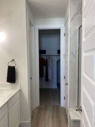 A modern bathroom with sleek fixtures, marble shower, and a spacious closet.
