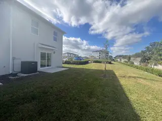 A modern home with a spacious backyard and lush landscape in Danbury at Ridgewood Lakes by D.R. Horton (Davenport, FL).