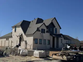 Street view A modern white brick home under construction in Homestead by Highland Homes, Schertz, TX.