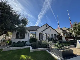 Street view A beautiful home with a stone exterior and well-maintained landscape in Palmera Ridge by Highland Homes (Leander, TX).