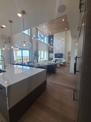 A luxurious open-concept space with a marble island, high ceilings, and chic lighting fixtures.