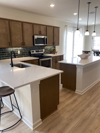 A modern kitchen featuring sleek wood cabinetry, elegant white countertops, and stylish pendant lighting.