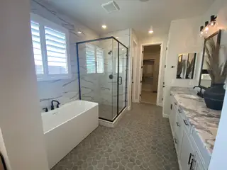 A luxurious bathroom with a sleek glass shower, freestanding tub, and double vanity atop patterned tile flooring.