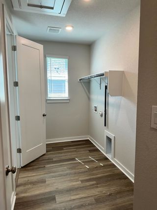A sleek laundry room with wood flooring, a utility shelf, and ample natural light through a small window.